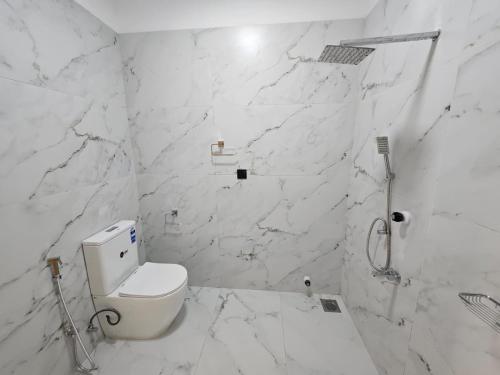 a white bathroom with a toilet and marble walls at AKR Rooms in Mannar