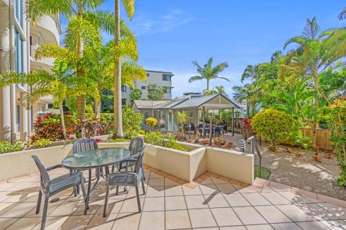 a patio with a table and chairs and trees at Alexandra on the Pacific in Mooloolaba