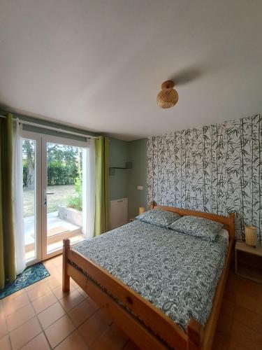a bedroom with a bed and a sliding glass door at Gîtes de l'AKWABA in Buzet-sur-Baïse