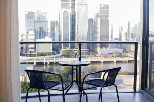 a table and chairs on a balcony with a view of a city at Lucid Apartment South Brisbane in Brisbane