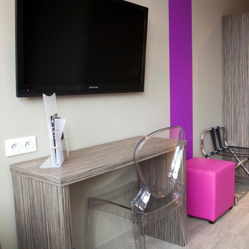 a flat screen tv on a wall with two chairs at ibis Styles Rennes St. Gregoire in Saint-Grégoire