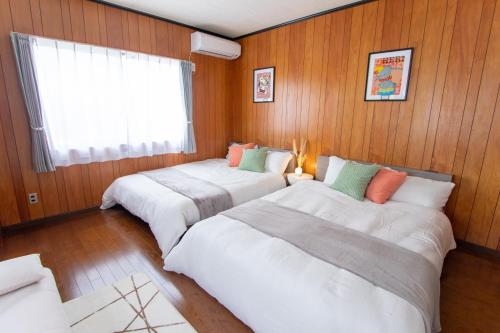 three beds in a room with wood paneled walls at YURURIBASE 凛 in Nagahama contactless checkin in Nagahama