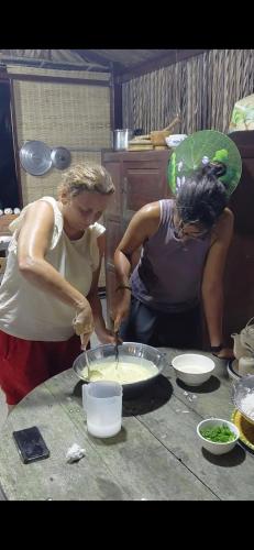 two women in a kitchen preparing food on a table at Onsen Cóc Retreat in My Tho