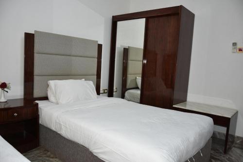 a bedroom with a large white bed and a mirror at Royal Suite Hotel Apartments in Al Ḩuwayl