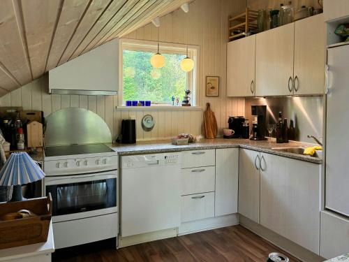 a kitchen with white cabinets and a window at Family Cabin By The Calm Waters Of Limfjord in Højslev