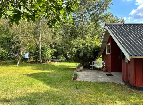 a red shed with a bench in a yard at Family Cabin By The Calm Waters Of Limfjord in Højslev