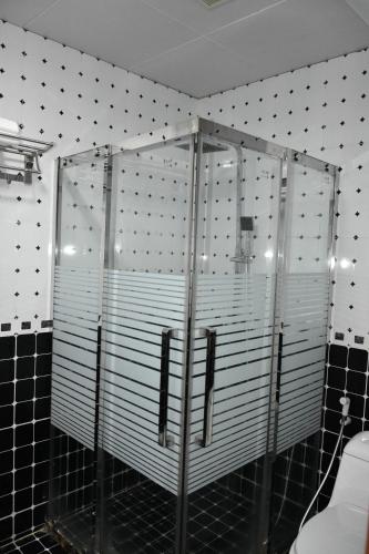 a shower in a bathroom with black and white tiles at Royal Suite Hotel Apartments in Al Ḩuwayl