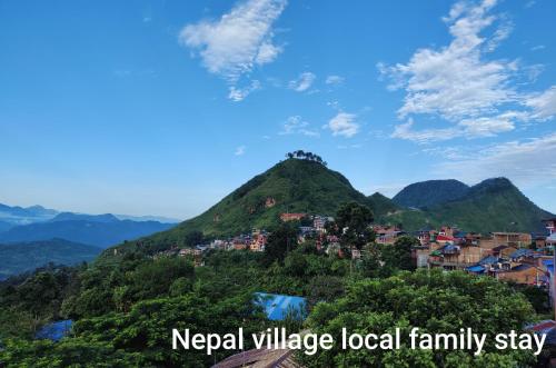 a village on a hill with mountains in the background at Nepal Village Local Family Stay - Ideal for Eco-Conscious Travelers in Bandipur