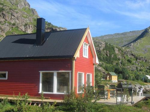 a red house with a table in front of a mountain at 6 person holiday home in Bøstad-By Traum in Tangstad
