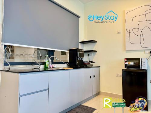 a kitchen with white cabinets and a black refrigerator at The Apple Residence By Heystay Management in Melaka