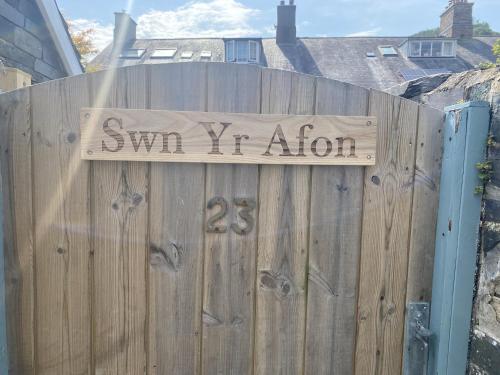 a wooden fence with a sign that reads swim iv infusion at Swn Yr Afon in Tywyn