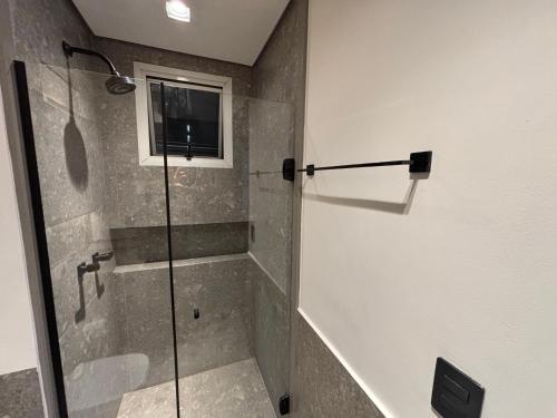 a bathroom with a shower with a glass door at Hotel Wynd Al Campinas Paulista Luxuoso com garagem piscina 1102 in Sao Paulo