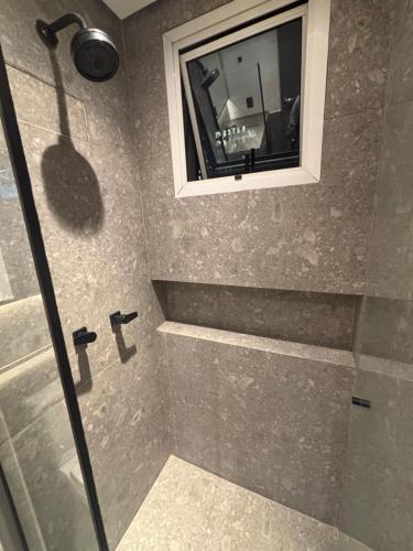 a bathroom with a shower with a window at Hotel Wynd Al Campinas Paulista Luxuoso com garagem piscina 1102 in Sao Paulo