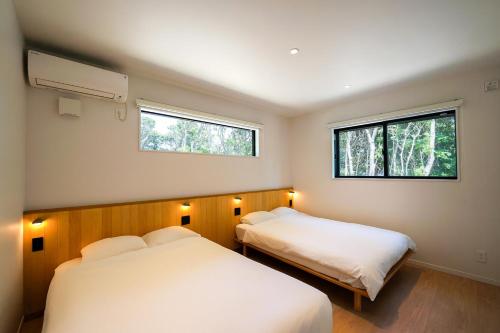 two beds in a small room with two windows at UMIBE Terrace in Shima