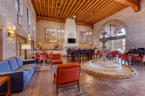 a living room with a blue couch and tables and chairs at Comfort Suites Tucson near Sabino Canyon in Tucson