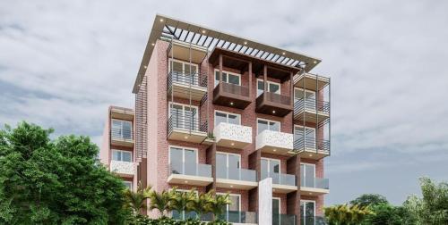 a tall brick building with balconies and trees at The Tomo Inn in Gurgaon