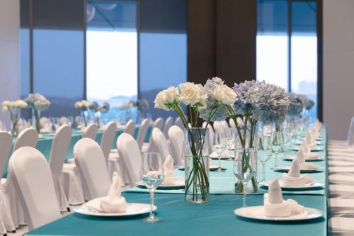 a long table with white chairs and vases of flowers at Vignette Collection The Xanadu Guangzhou, an IHG Hotel in Guangzhou