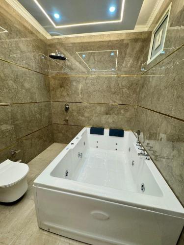 a white bath tub in a bathroom with a toilet at The Classic Crowne at Delhi Airport in New Delhi