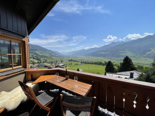 a wooden table and chairs on a balcony with mountains at Chalet on the slopes in Piesendorf