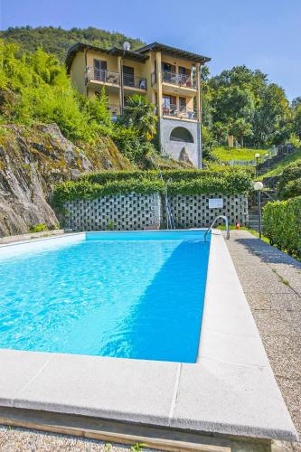 a blue swimming pool in front of a house at Residenz La Fonte Studios in Pino Lago Maggiore