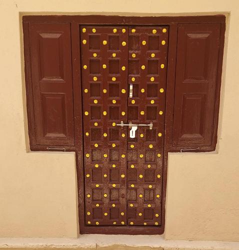 a wooden door with gold dots on it at The Imperial Regency in Porbandar