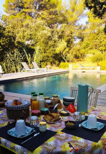 a picnic table with food and drinks next to a pool at la bergerie des colles in Entrecasteaux