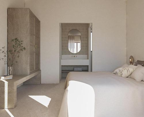 a white bedroom with a bed and a mirror at villas cape in Plateies