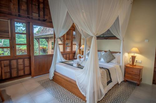 a bedroom with a canopy bed with curtains at Kerjim Wooden Villa in Ubud