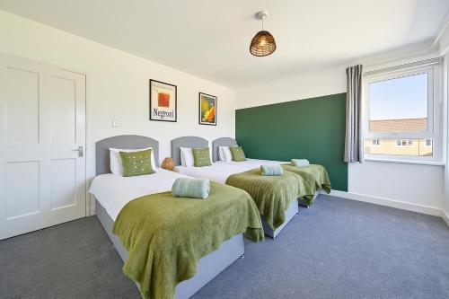 een slaapkamer met drie bedden met groen en wit bij Walk to Hydro and SEC Modern 3BR Free Parking in Glasgow