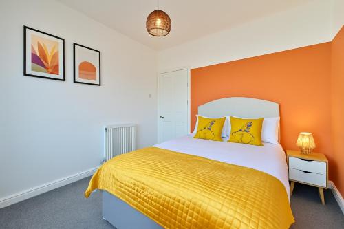 a bedroom with a bed with an orange wall at Walk to Hydro and SEC Modern 3BR Free Parking in Glasgow
