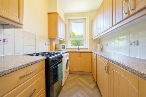 a kitchen with wooden cabinets and a stove top oven at Walk to Hydro and SEC Modern 3BR Free Parking in Glasgow