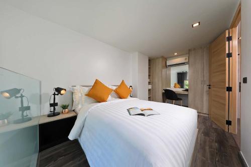 ラワイビーチにあるDuplex 1 BR Direct Pool Access A114のオレンジ色の枕が付いた大きな白いベッドのある寝室