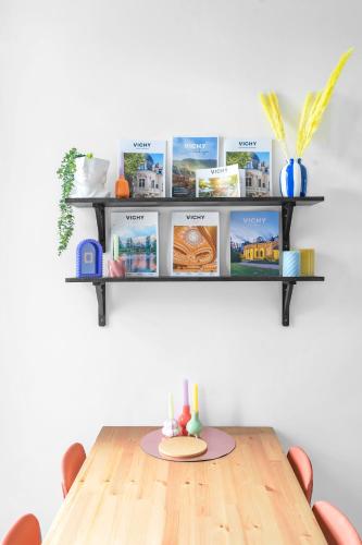 a table with chairs and a shelf with books at Le Beaulieu - Appartement lumineux, stationnement gratuit in Vichy