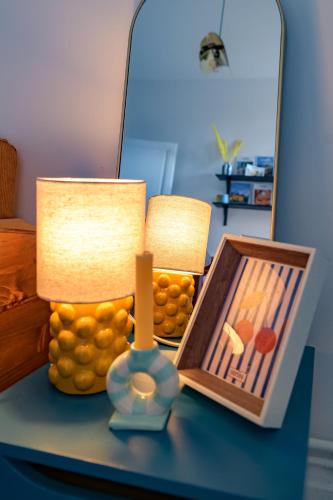 a table with two lamps and a picture and a mirror at Le Beaulieu - Appartement lumineux, stationnement gratuit in Vichy