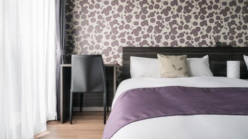 a bedroom with a bed and a patterned wall at BON Condominium Namba Ebisu in Osaka
