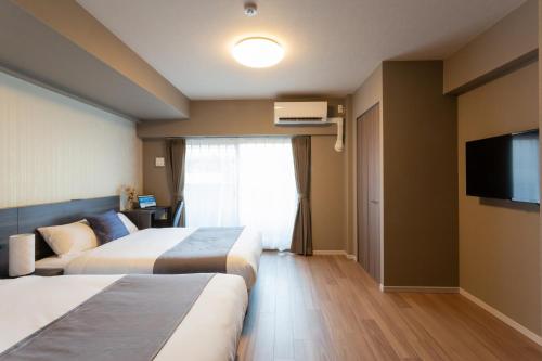a hotel room with two beds and a flat screen tv at BON Condominium Namba Ebisu in Osaka