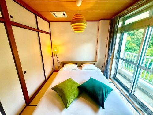 a bedroom with a bed with two pillows and a window at FujiteraCanvas201 in Gotemba