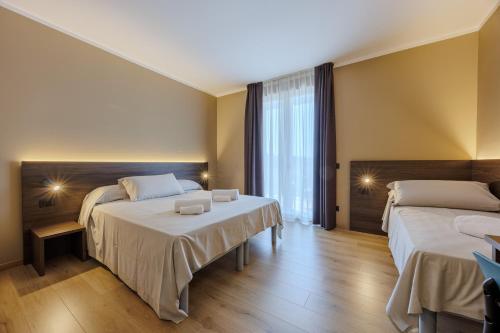 a hotel room with two beds and a window at Hotel San Marco in Bardolino