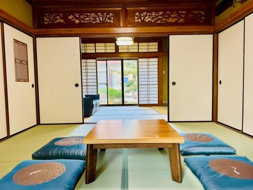a room with a wooden table and blue cushions at 風光乃邸宅 ハナレ Fuukou no Teitaku HANARE in Shirahama