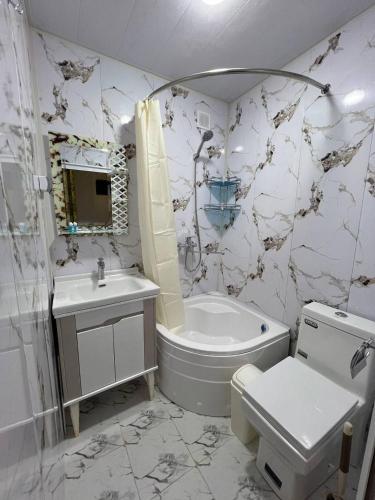 a bathroom with a tub and a toilet and a sink at Zardozon Hotel in Bukhara