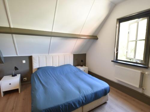 a bedroom with a blue bed and a window at Apartment Sint Maartensbrug near Beach in Sint Maartensbrug