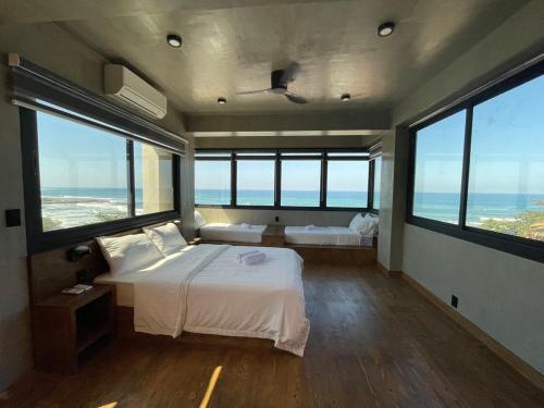 a bedroom with a large bed and large windows at A-Lofts Sky Suite amazing beachfront 360 sea view in San Juan