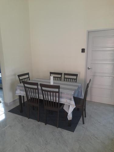 a dining room table with chairs and a white door at Marissa Homestay 
