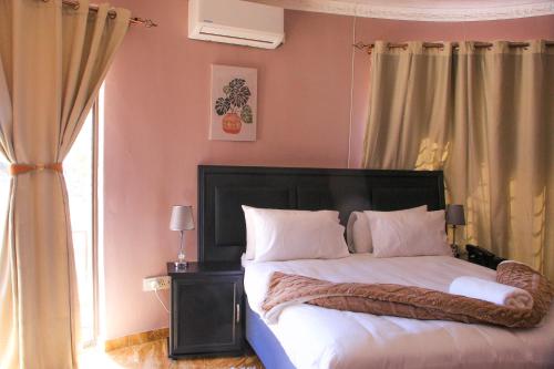 a bedroom with a bed with white sheets and a window at Masiyabundu chalets in Gaborone