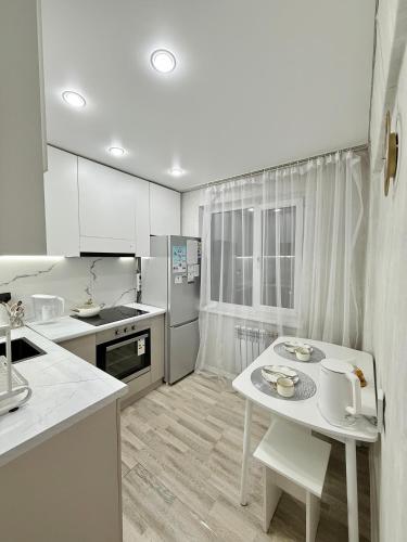 eine Küche mit weißen Schränken und einem weißen Tisch in der Unterkunft 1,5-комнатная квартира в центре города in Öskemen