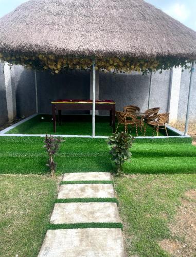 a grass umbrella with a table and chairs in a yard at Pinnacle-Plus Service Apartment in Akure Airport