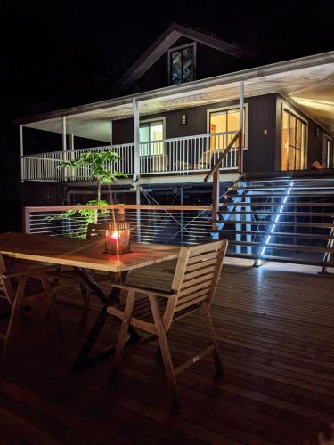 a wooden table and chairs on a deck at night at Shangri-La! Secluded & Lush Country Property in Kin Kin
