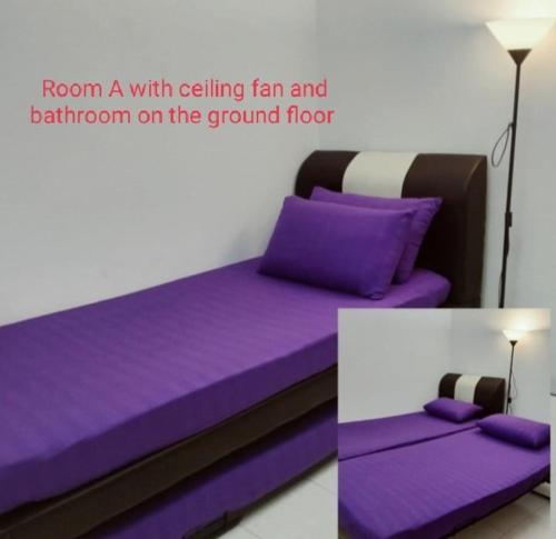 a bed with purple sheets and a lamp on the ground floor at 4-room double storey house, 10km KLIA in Sepang