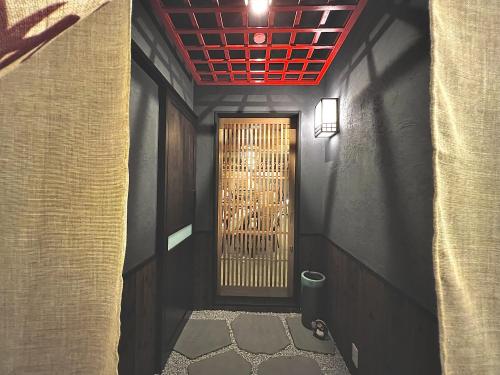 a hallway with a door with a red ceiling at おおさか城北 宿福 in Osaka