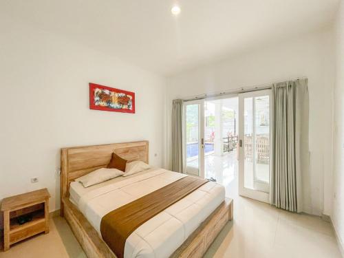 a bedroom with a bed and a large window at Urbanview Hotel Lilis Ikvala Radha in Canggu